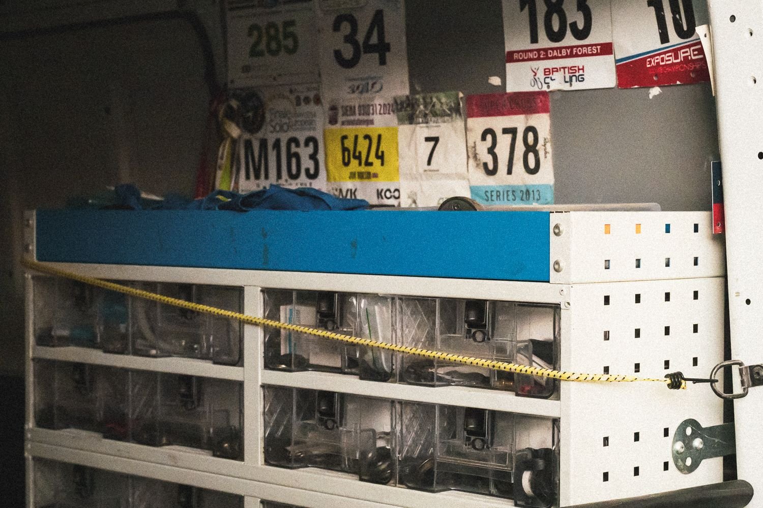 Support van shelving with parts boxes and old race numbers pinned above