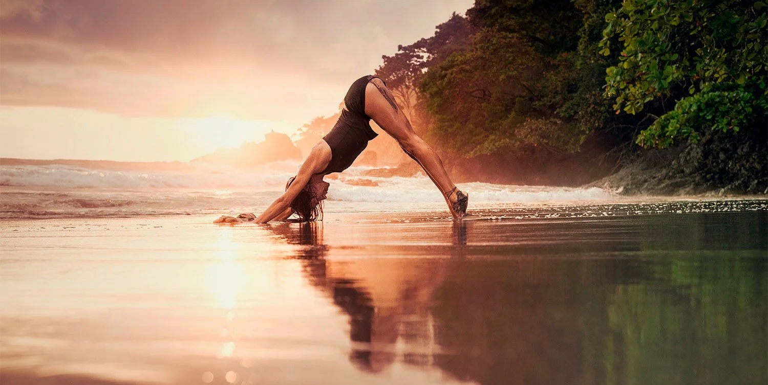 Downward dog on wet sand at sunset, from a wellbeing retreat commission photographed by Karen Yeomans
