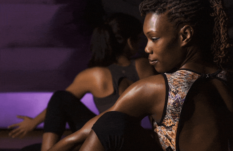 Hotpod Yoga class practising side stretches in the studio's purple-lit pod