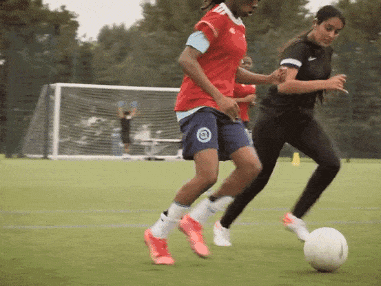 Women's football match seen through the goal net at a London pitch