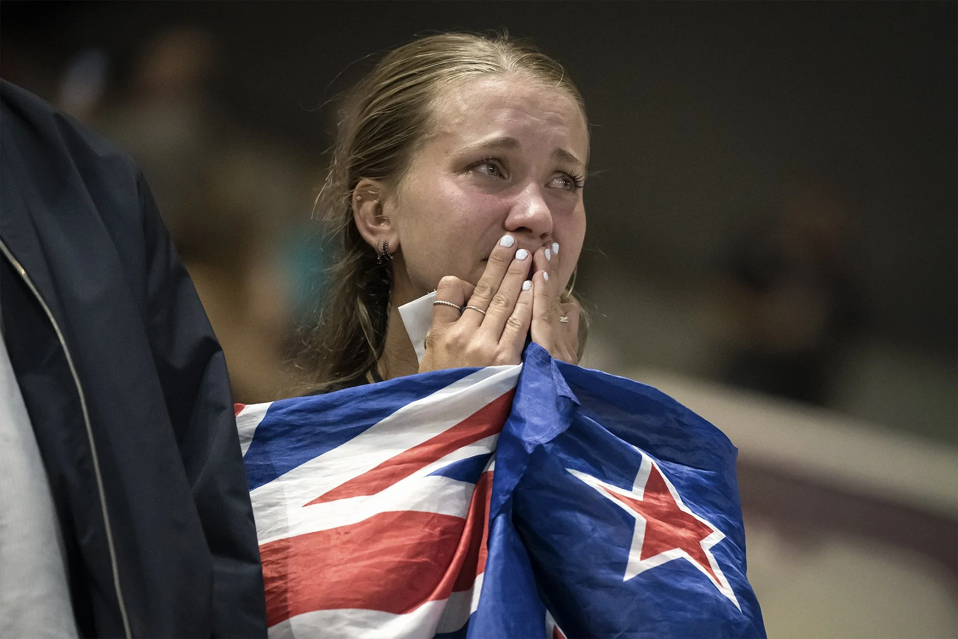A New Zealand supporter wrapped in a flag reacts to semi-final defeat, Women's Rugby World Cup 2025, by Karen Yeomans