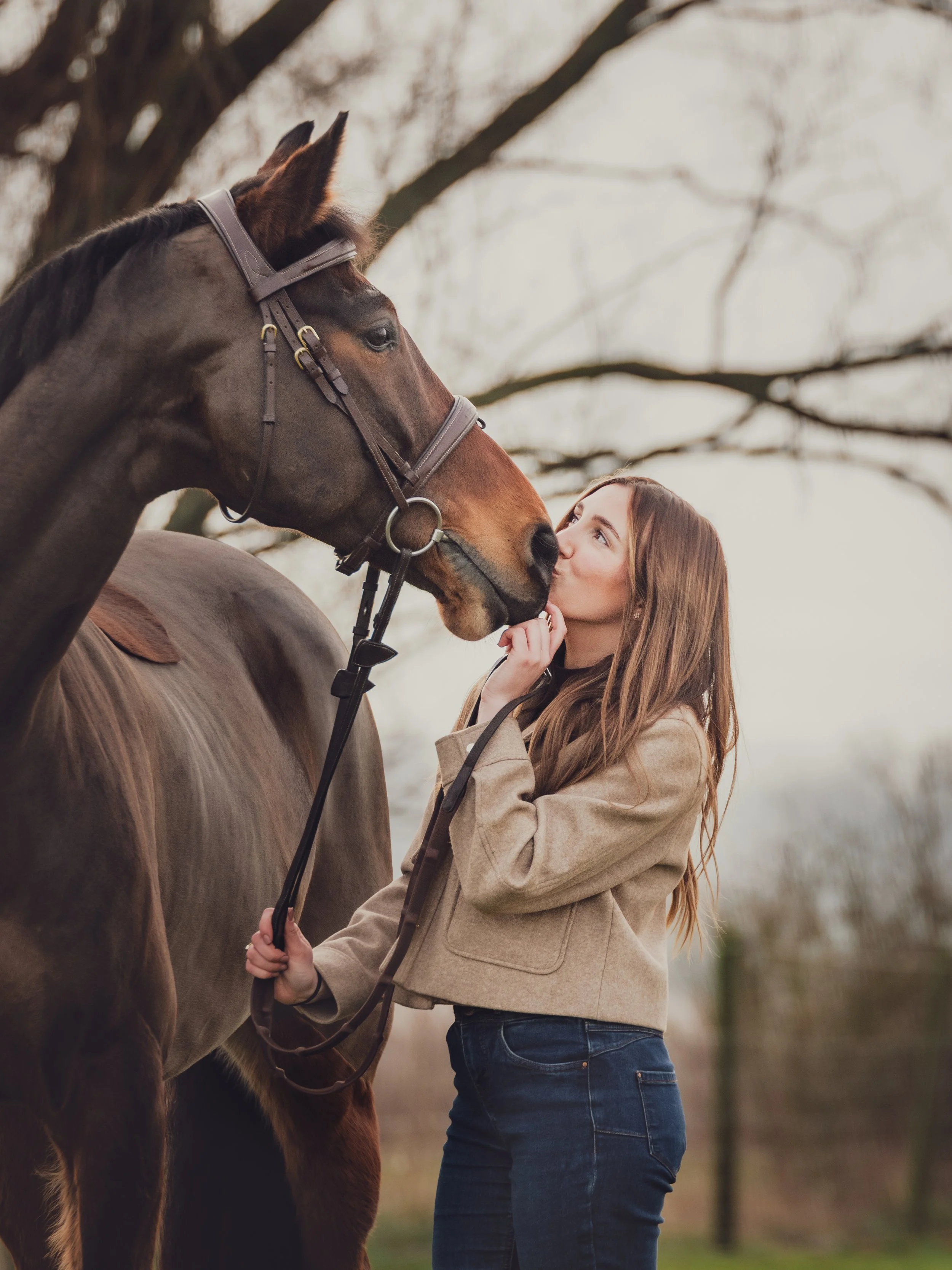 portrait owner kissing horse nose in winter
