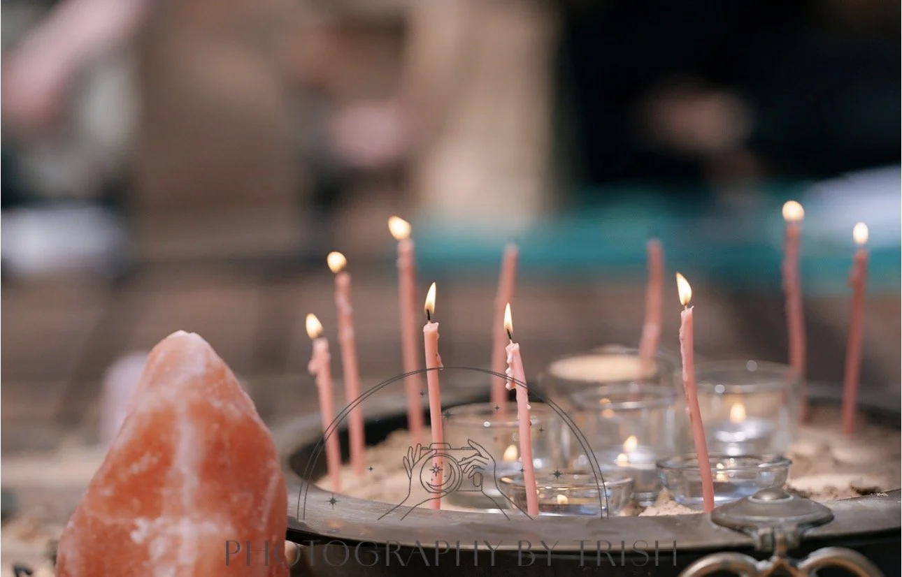 Pink candles burning in glass holders, salt lamp on left, and blurred background.