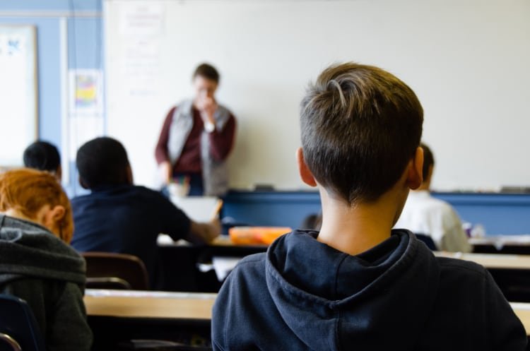 Boy in blue hoodie sitting in a classroom