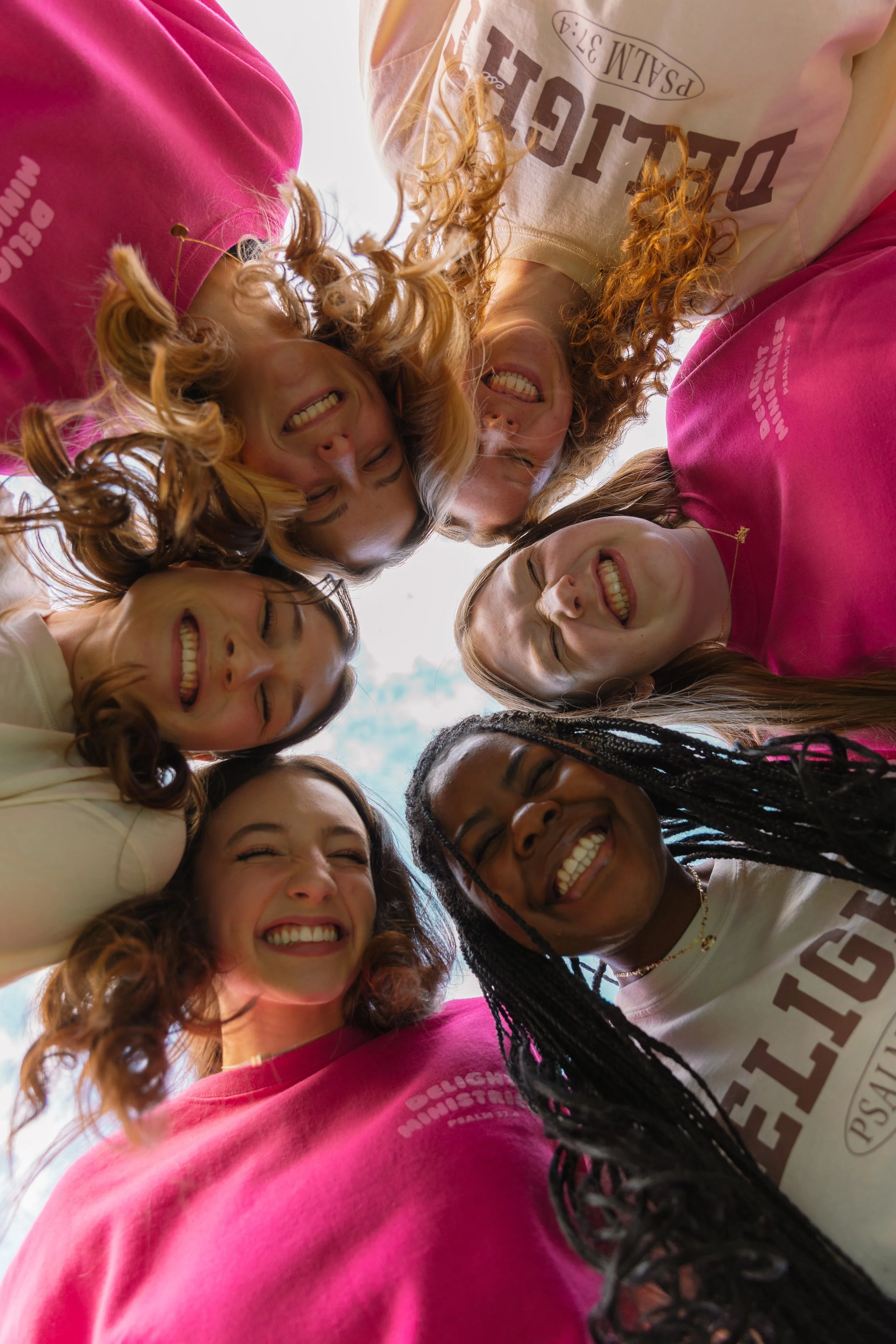 A huddle of Delight women gathered around smiling, wearing Delight merchandise.