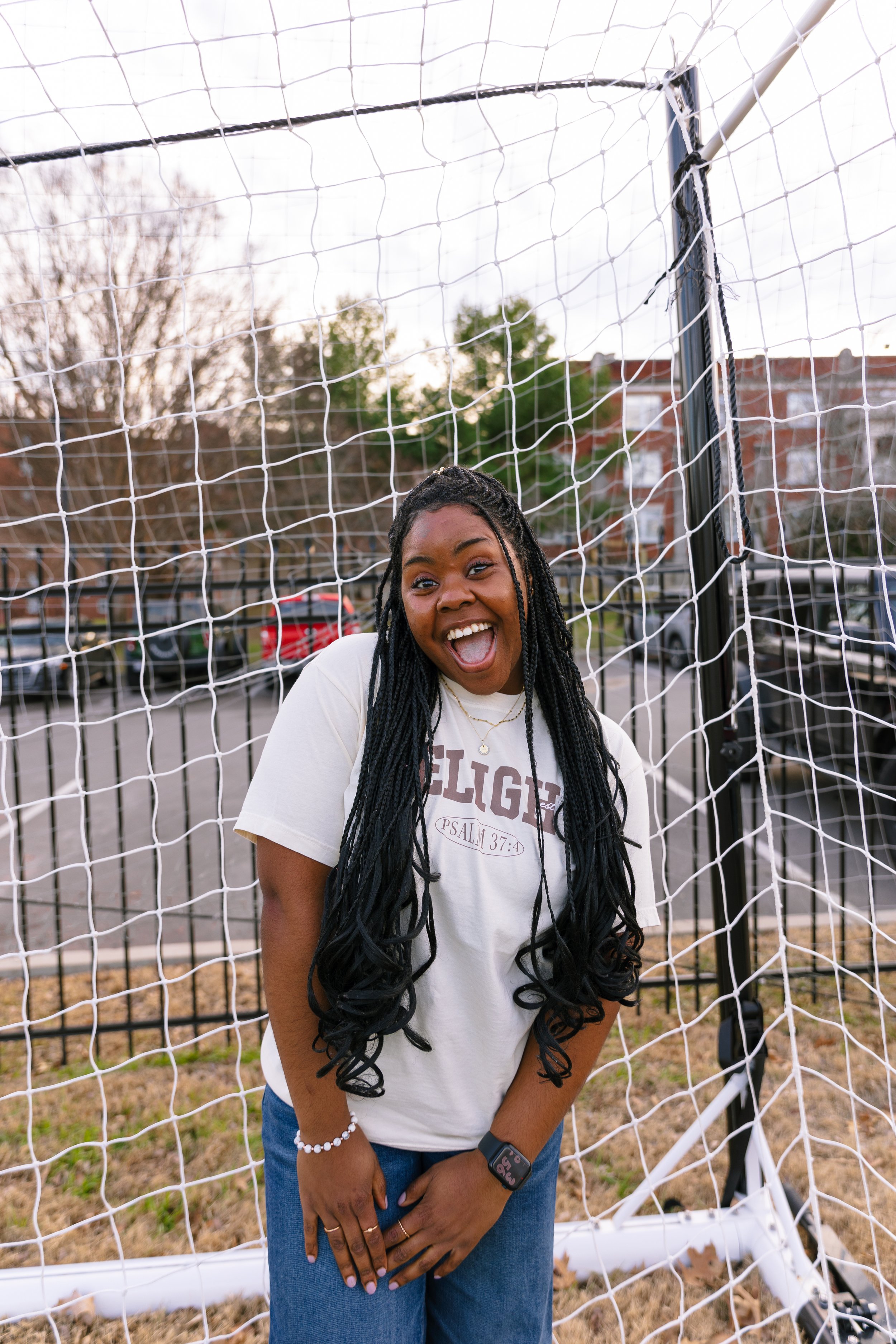 A picture of a girl wearing a Delight t-shirt in front of a soccer goal.
