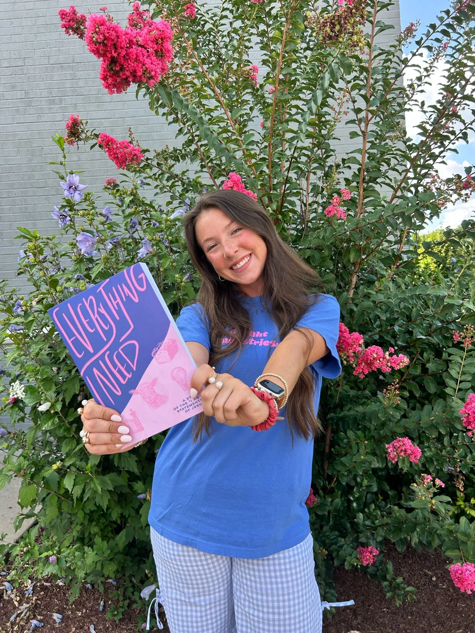 A girl wearing a blue Delight Ministries t-shirt holding up the Delight Bible study, "Everything I Need".
