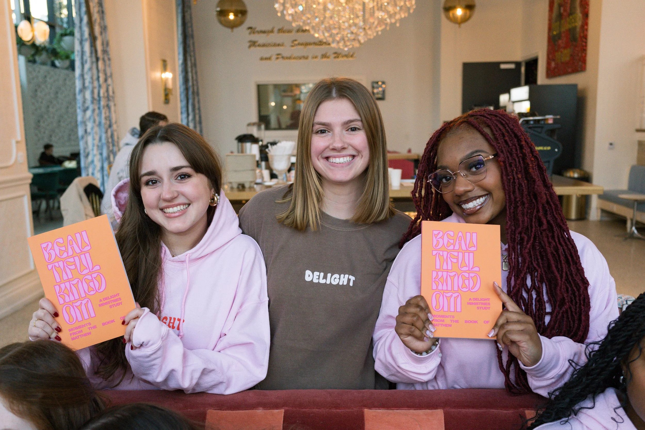 3 women in Delight merchandise with two holding up "Beautiful Kingdom", a Delight Bible study.