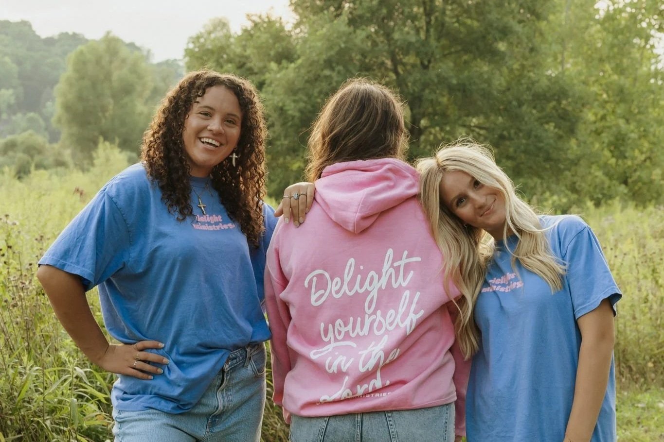 3 women wearing Delight merch outside standing together.