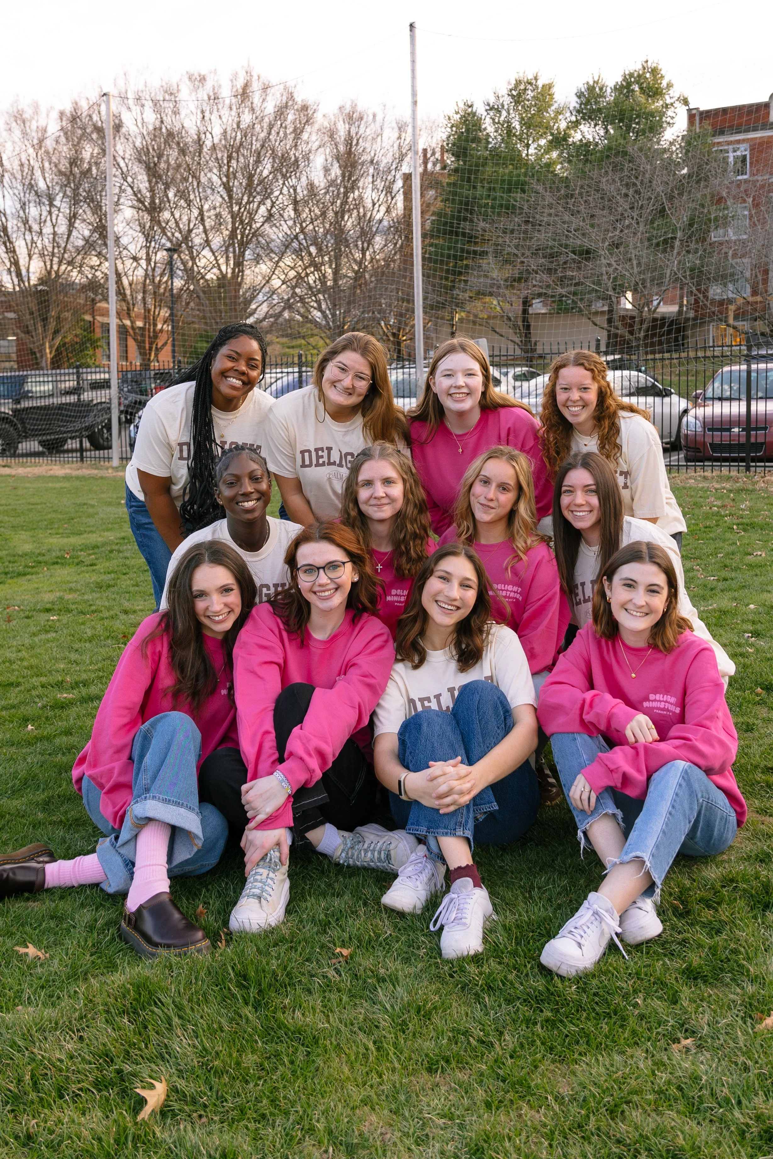 A group of Delight girls wearing Delight merch in a field by a soccer goal.