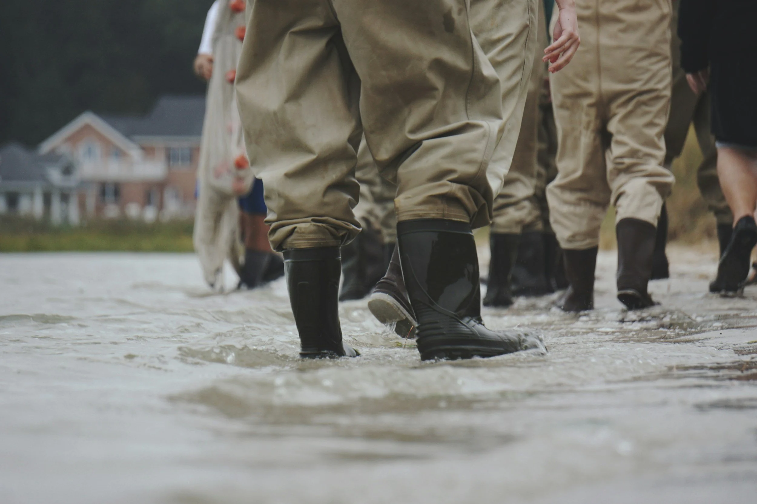 Emergency responders moving through flood conditions, highlighting the need for rapid emergency lodging solutions supported by Lima Charlie Inc.