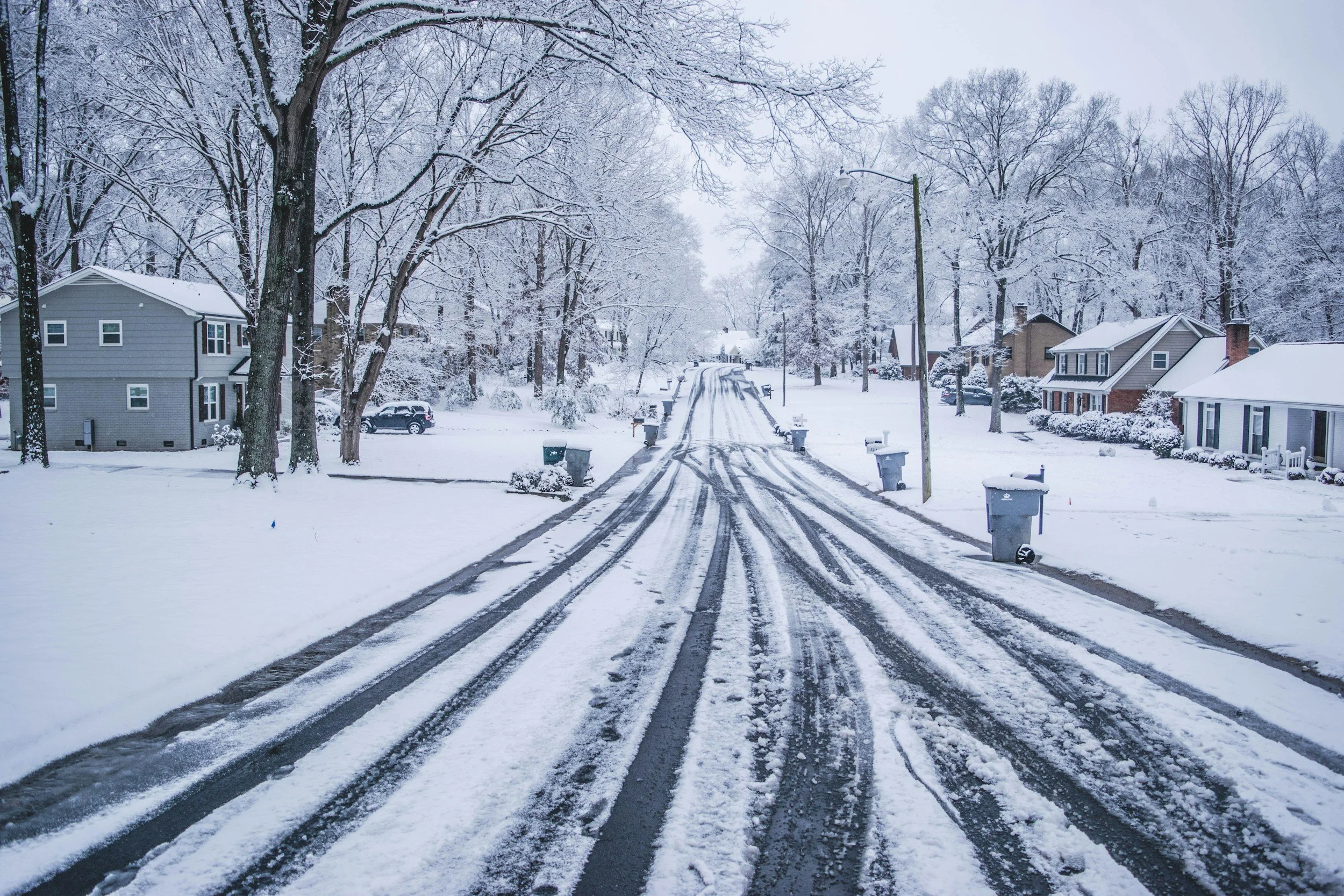 Residential street covered in snow after a winter storm, illustrating emergency lodging and community access challenges coordinated by Lima Charlie Inc.