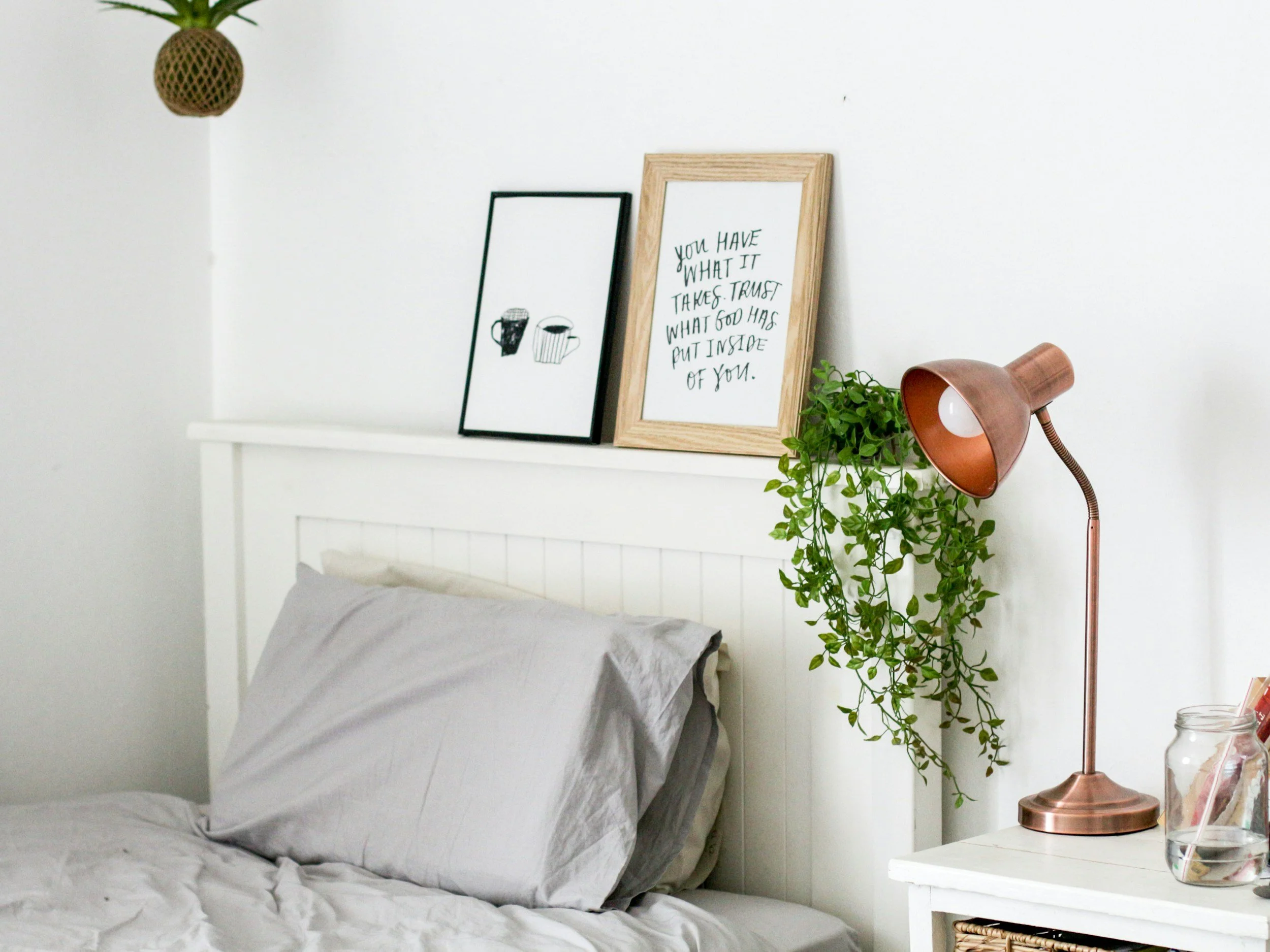 A clean, comfortable bedroom with soft grey bedding and warm decor, representing the move-in-ready furnished housing Lima Charlie Inc. provides for corporate relocation, student placements, and workforce deployments nationwide.