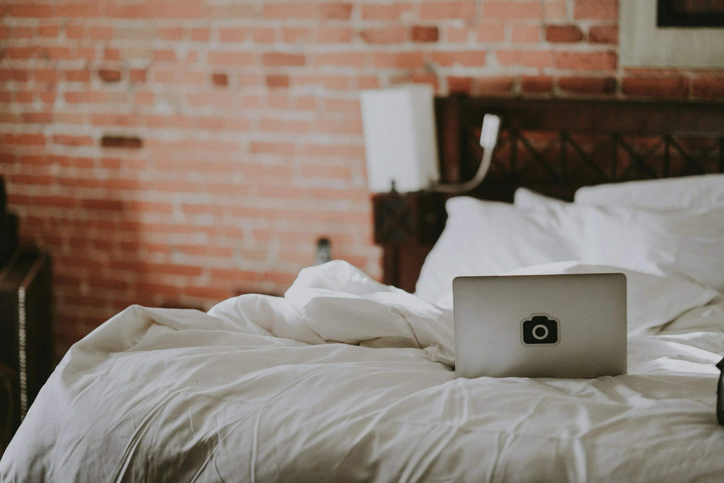 A laptop on a made bed in a furnished room, reflecting the work-ready, connected living environments Lima Charlie Inc. delivers for traveling professionals, relocating employees, and extended-stay workforce deployments.
