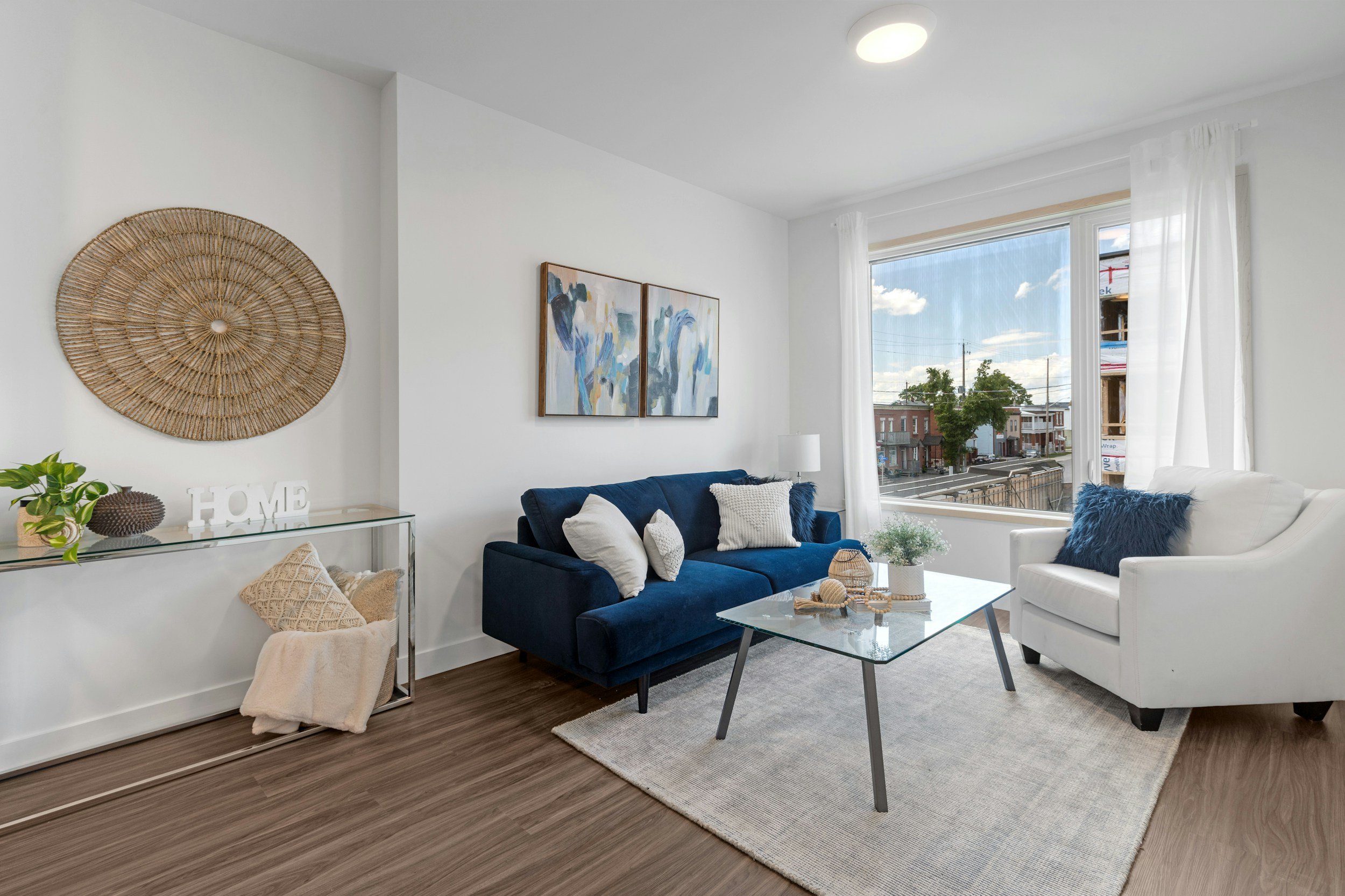 A furnished living room with a navy blue sofa, white armchair, and glass coffee table, the kind of move-in ready furnished apartment Lima Charlie Inc. provides for PCS housing placements.