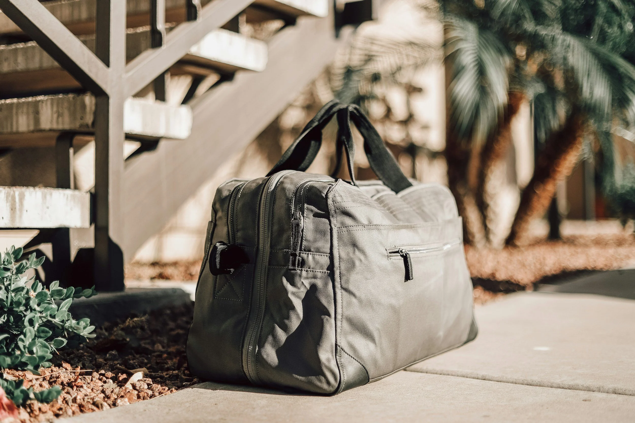 An olive green duffel bag packed and ready beside an apartment stairwell, capturing the readiness Lima Charlie Inc. brings to every PCS housing and military family relocation.
