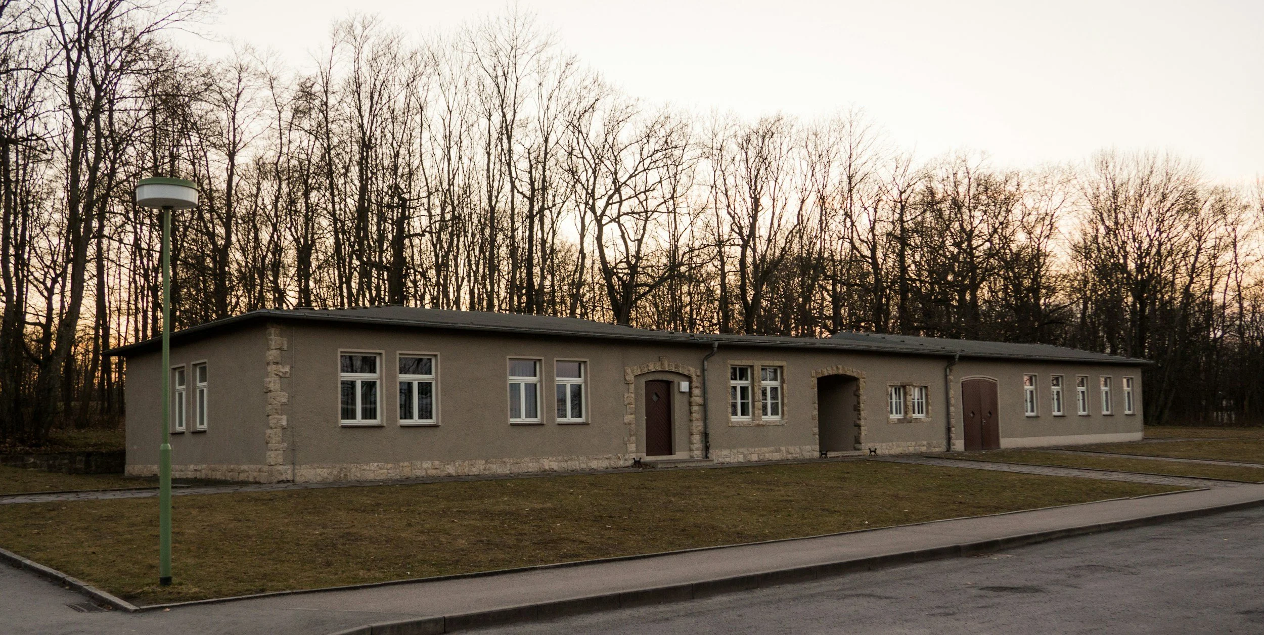 A long, single-story barracks-style building sits among bare winter trees, the kind of on-post housing junior sailors sometimes wait years for while Lima Charlie Inc. offers move-in ready alternatives now.