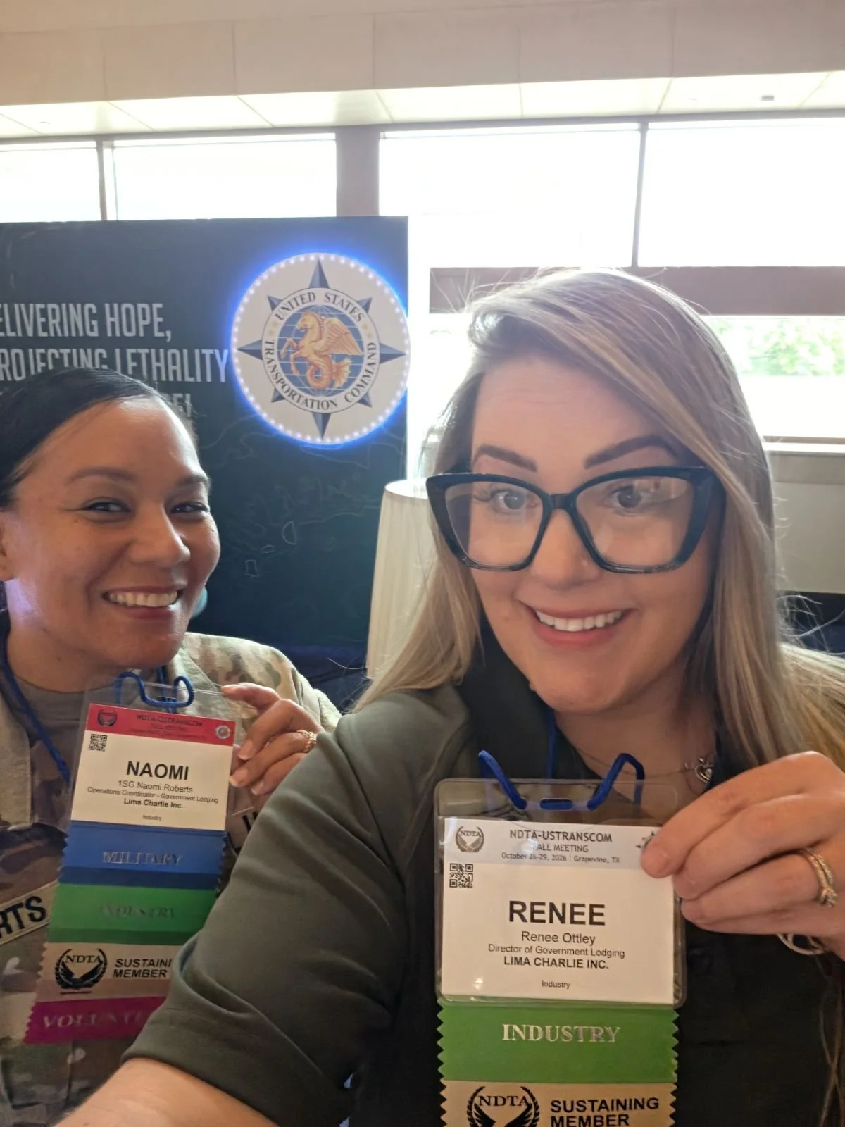 Naomi Roberts and Renee Ottley of Lima Charlie Inc. holding their NDTA-USTRANSCOM Fall Meeting badges, the Government Lodging team behind our government lodging services.