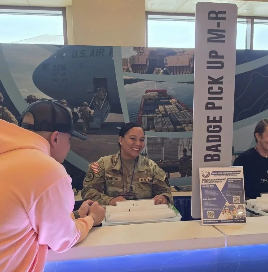 Naomi Roberts of Lima Charlie Inc. in her Army uniform helping an attendee at the NDTA badge pickup desk, part of the government lodging team at the Fall Meeting.