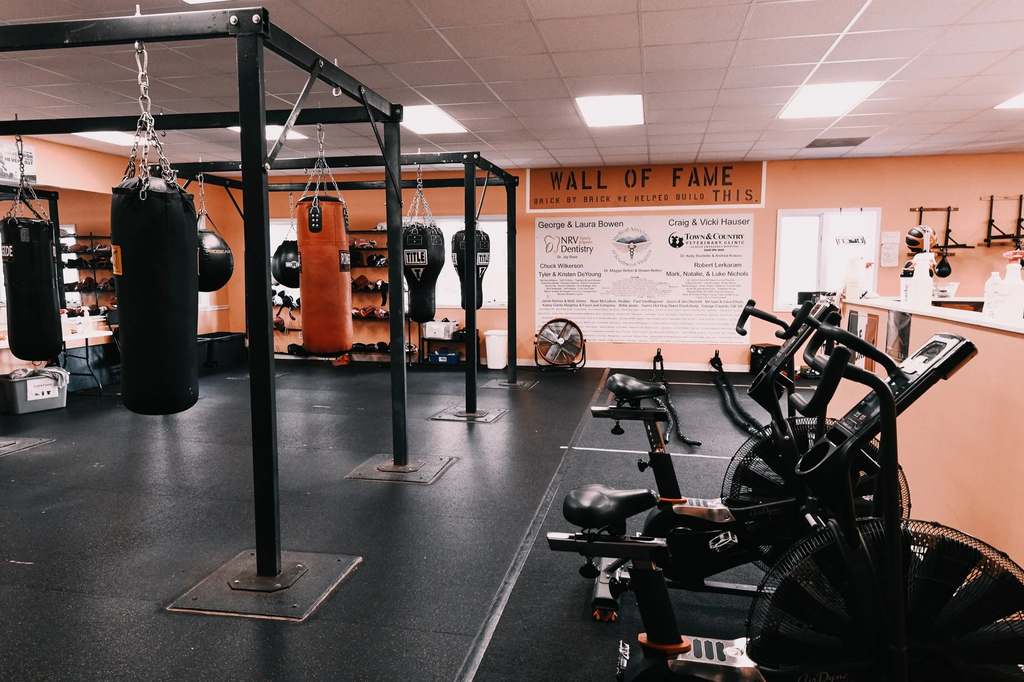 Gym with punching bags, stationary bikes, and a wall of shoes and equipment.