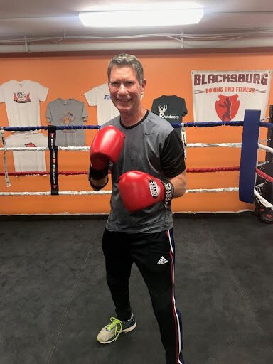 A man in boxing gloves standing inside a boxing ring.