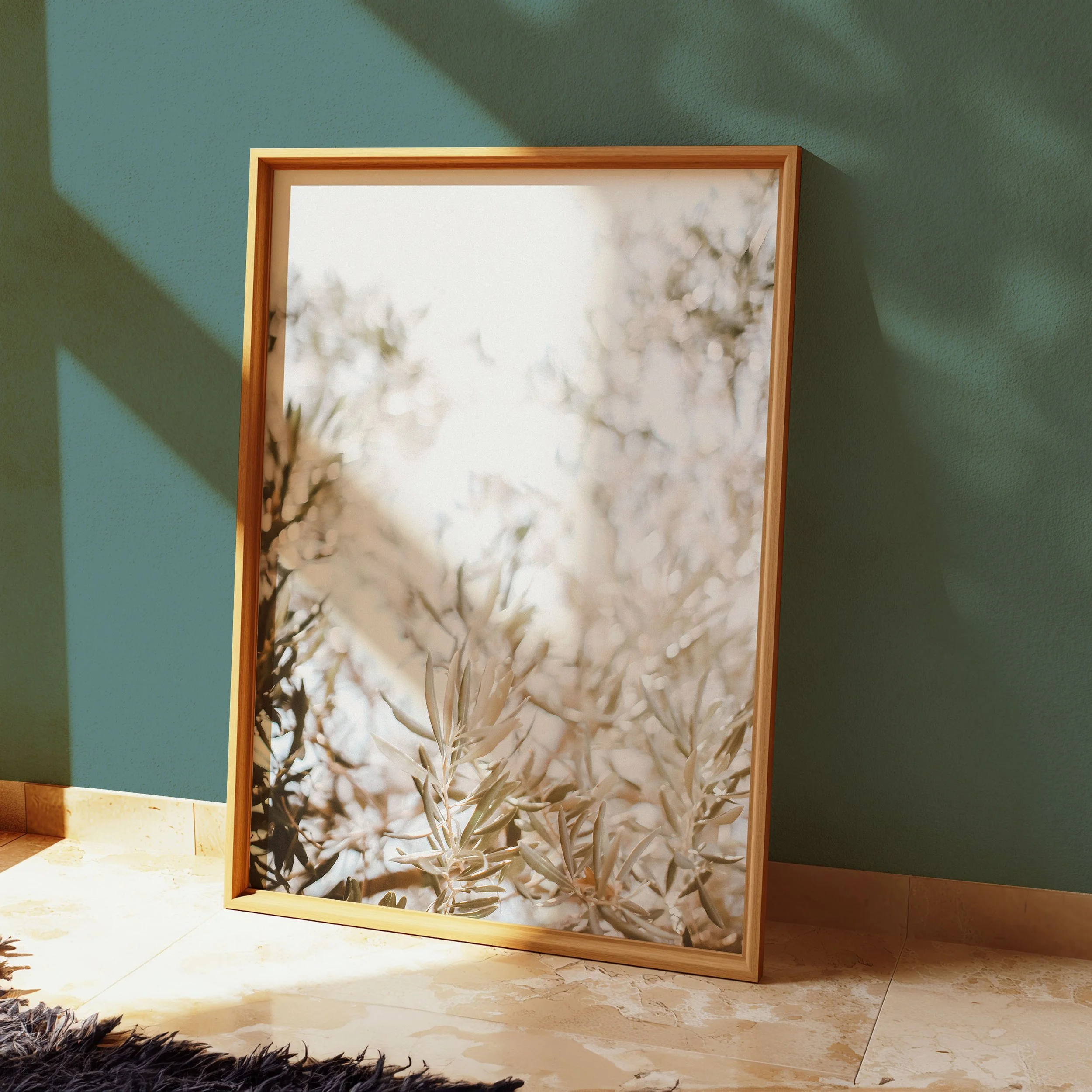 A framed mirror leaning against a green wall, reflecting sunlight and a blurred view of tree branches with leaves.