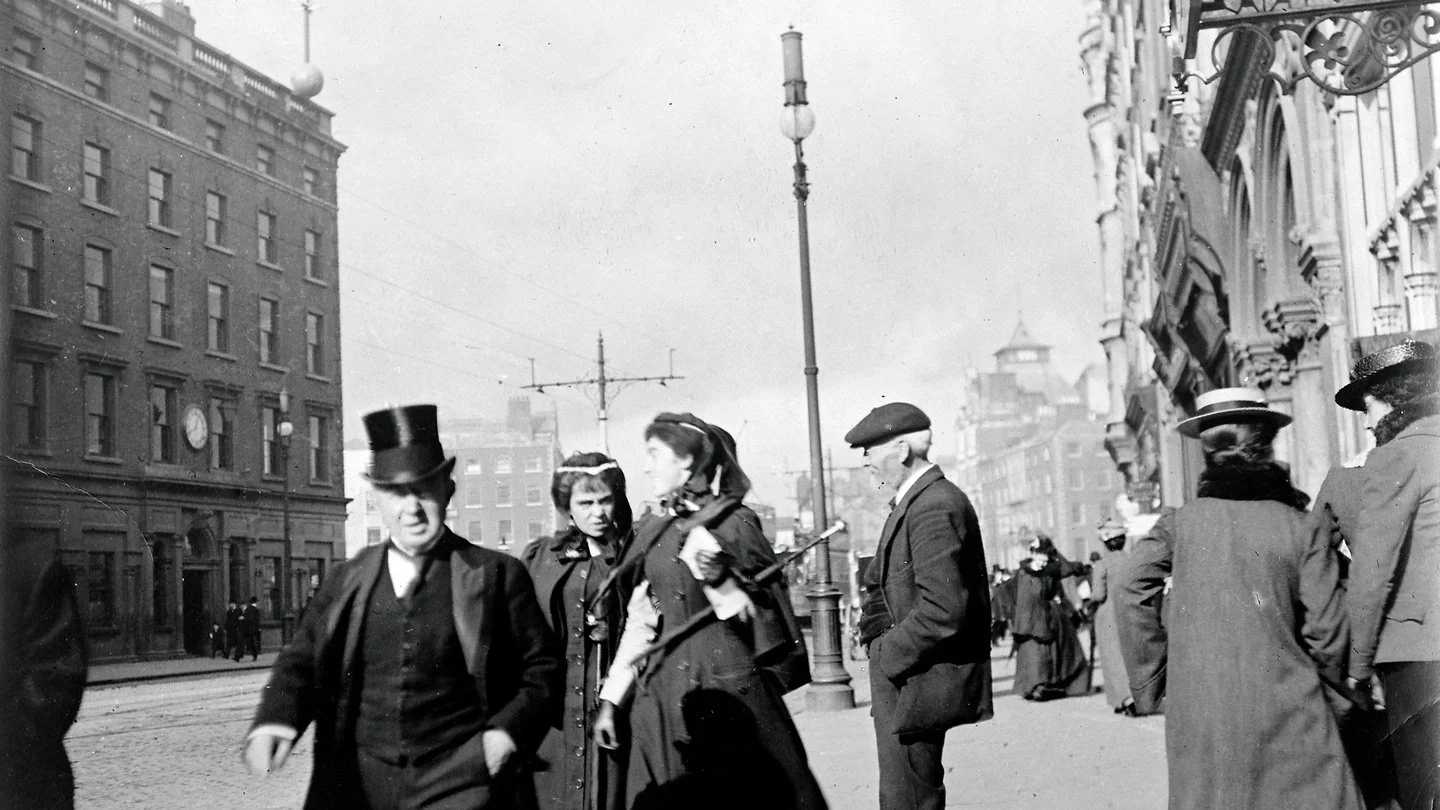 People walking on Westmoreland St., Dublin, c. 1901-1904; the timeball and east-facing clock can be seen on the Ballast Office to the left. (Image Source: https://catalogue.nli.ie/Record/vtls000168763 )
