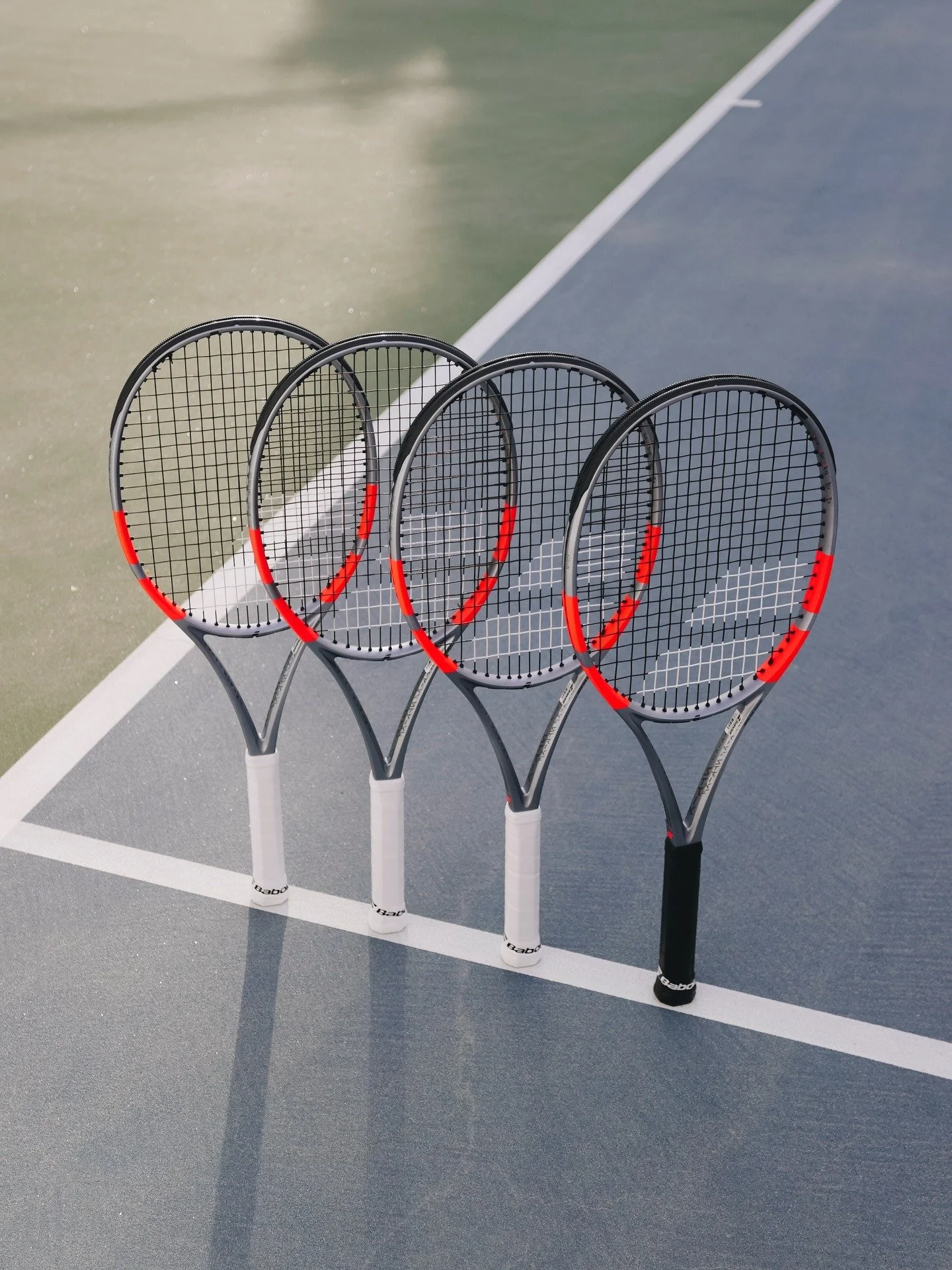 Four tennis racquets stand independently along a tennis court line.
