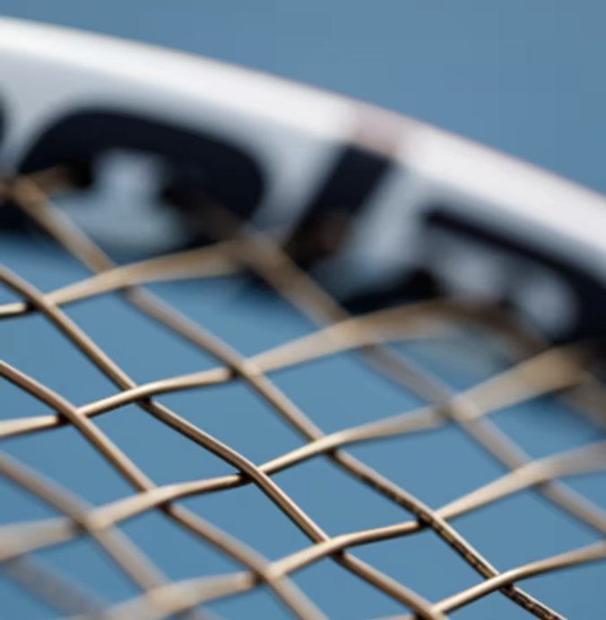 Close-up of a tennis racquet's strings with a blue background.