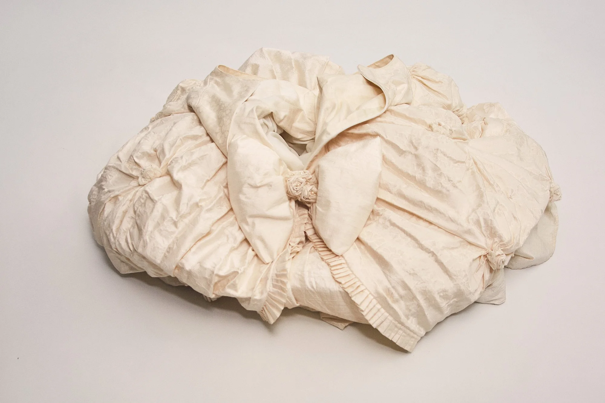 Photograph of an empty dress lying on the floor in a symbolic closing image from the series Cuerpo Vestido, Alma Desnuda by Beatriz Perez.
