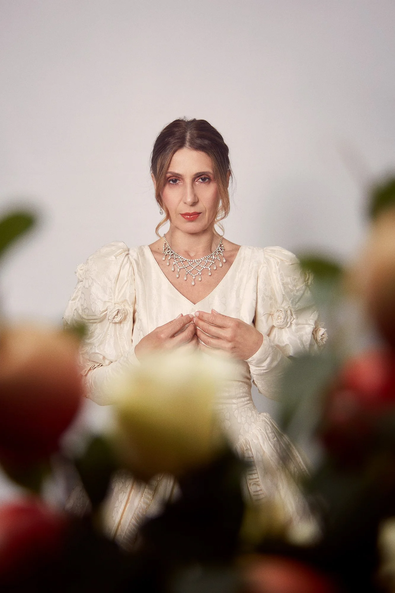 Portrait photograph of La Novia framed by flowers in an introspective pose from the series Cuerpo Vestido, Alma Desnuda by Beatriz Perez.