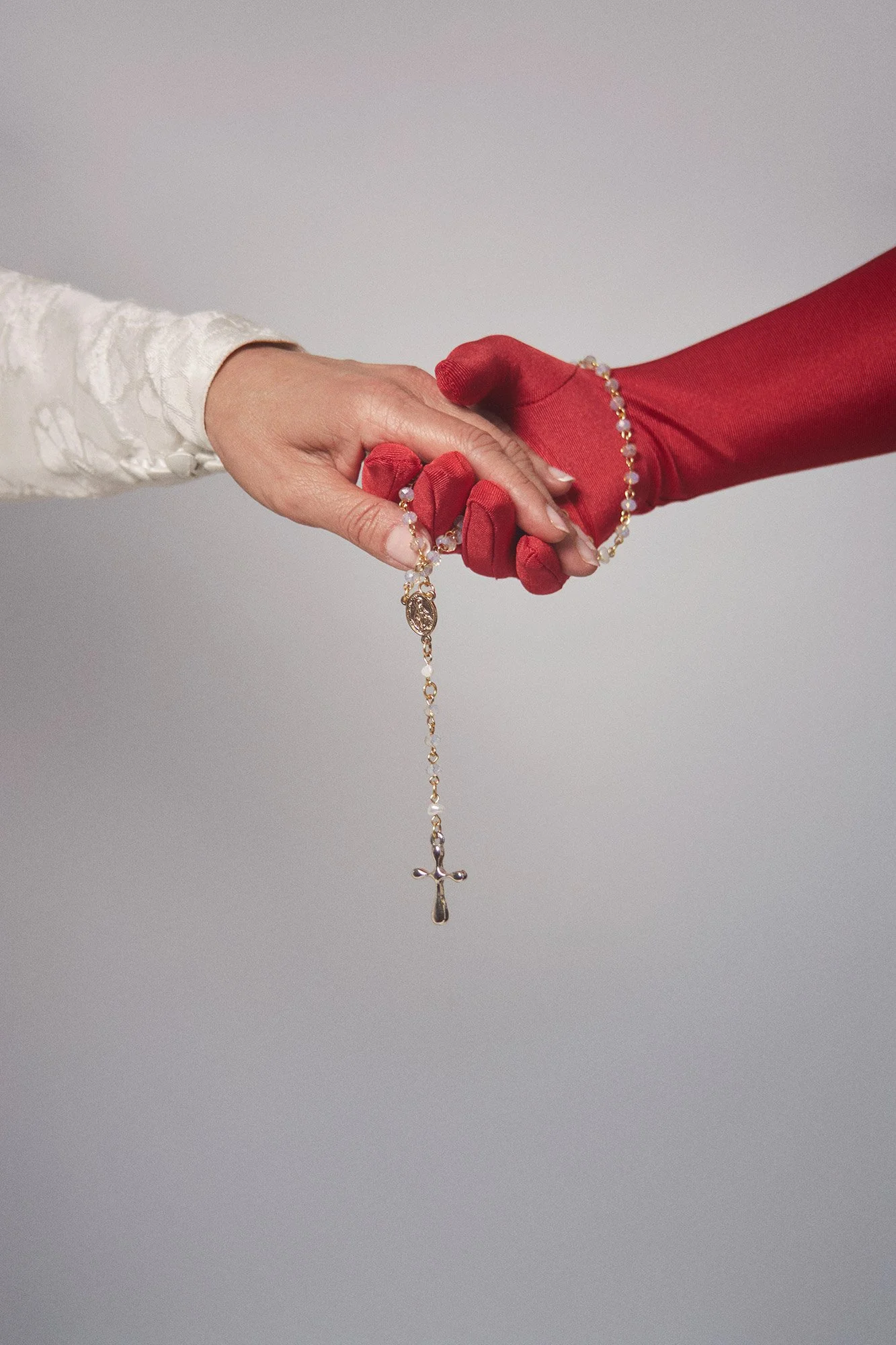 Close-up photograph of La Novia holding a rosary with beads in a symbolic gesture from the series Cuerpo Vestido, Alma Desnuda by Beatriz Perez.
