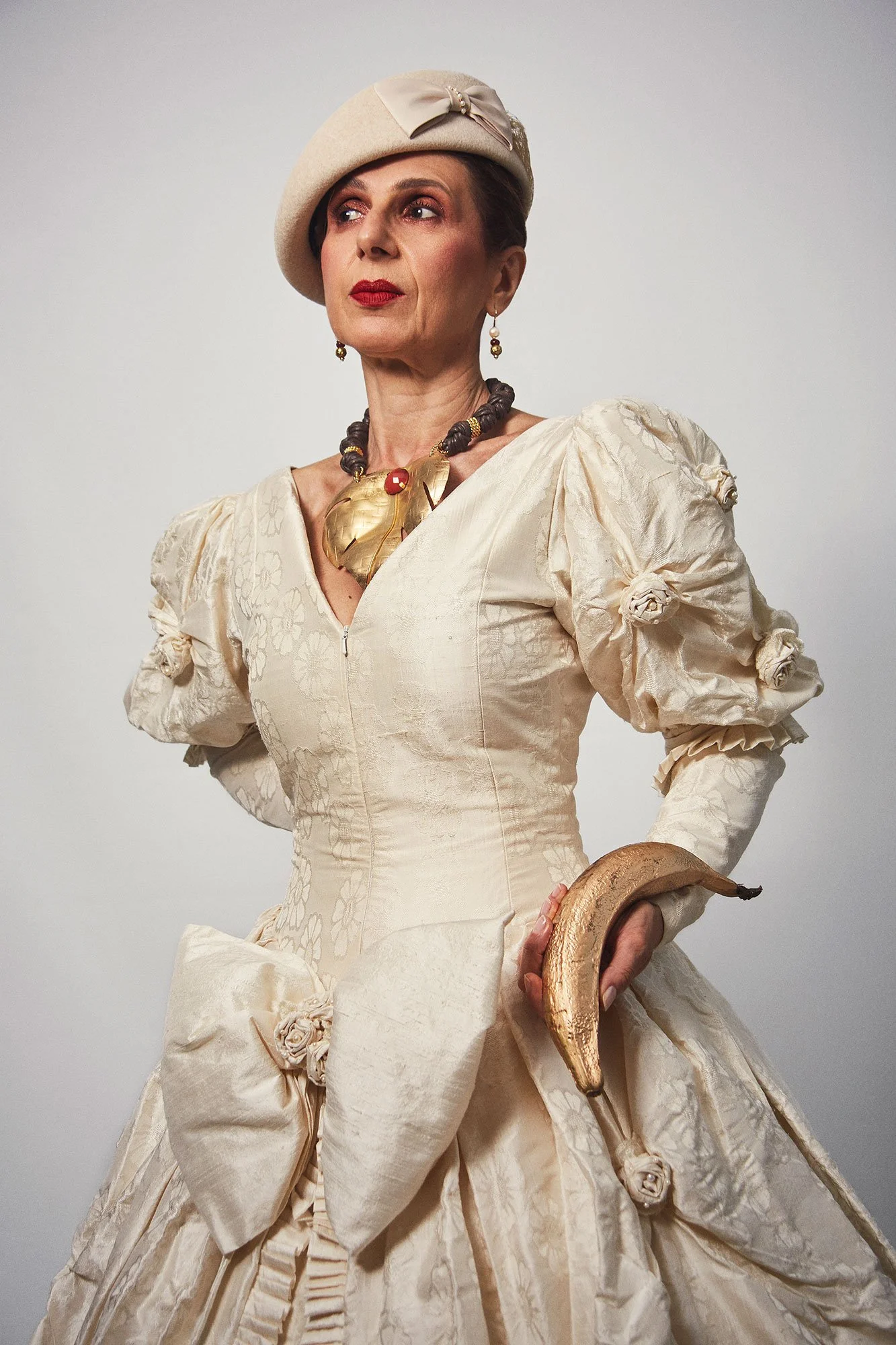 Portrait photograph of La Doña holding a plantain in a symbolic gesture from the series Cuerpo Vestido, Alma Desnuda by Beatriz Perez.