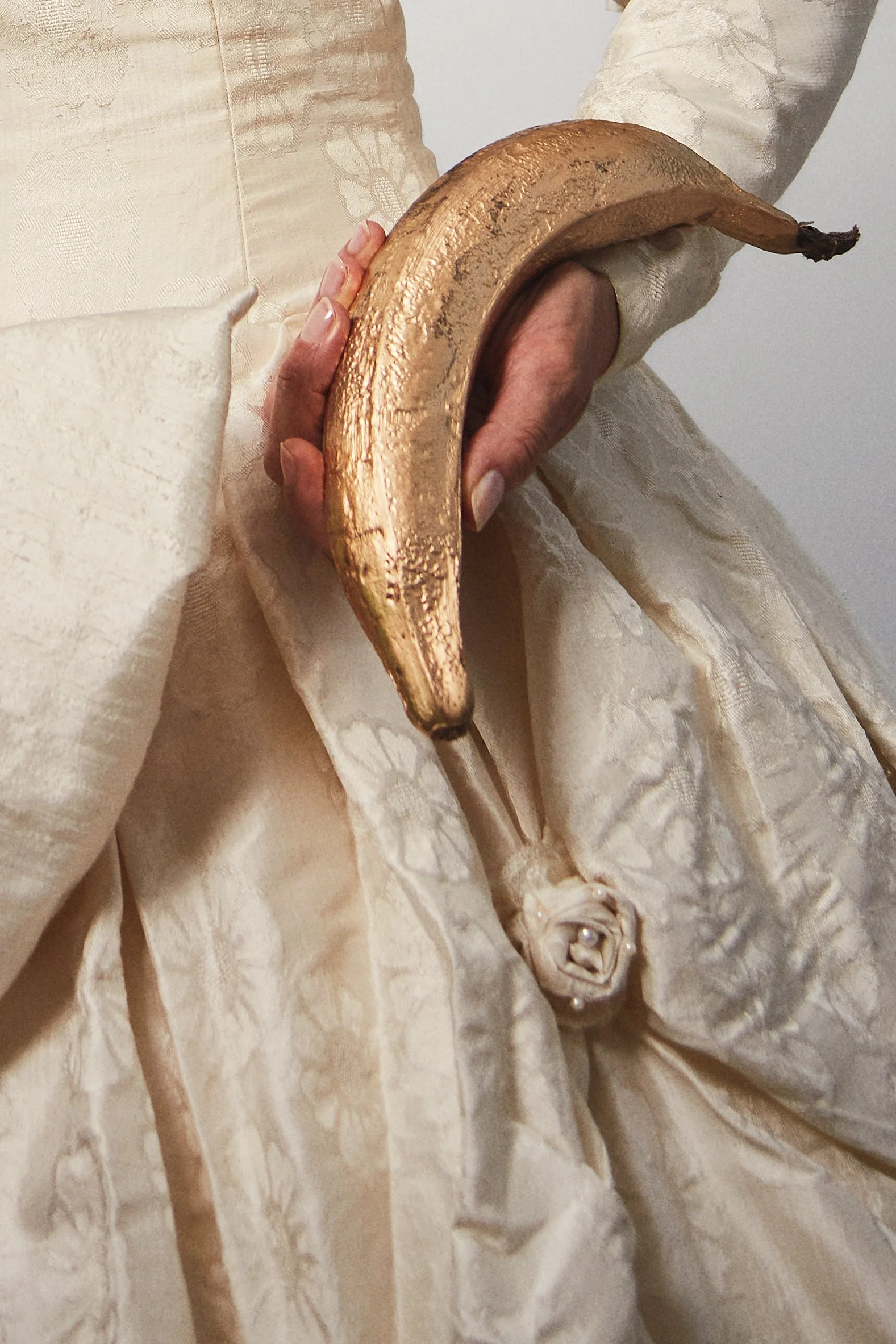 Close-up photograph of La Doña holding a plantain in her hand in a symbolic gesture from the series Cuerpo Vestido, Alma Desnuda by Beatriz Perez.