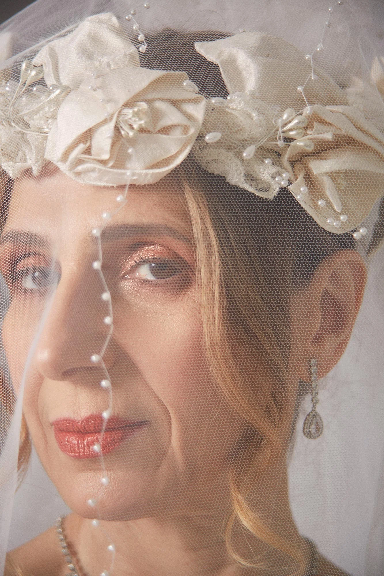 Close-up portrait photograph of La Novia wearing a veil with a string of pearls across her face from the series Cuerpo Vestido, Alma Desnuda by Beatriz Perez.