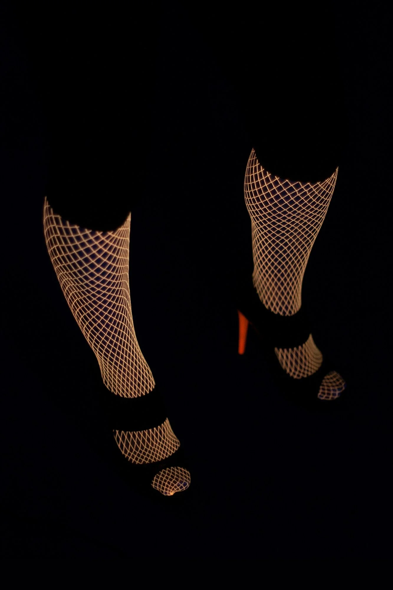 Photograph of female legs in fishnet stockings and stilettos positioned apart in a graphic composition from the series MISShapes by Beatriz Perez.