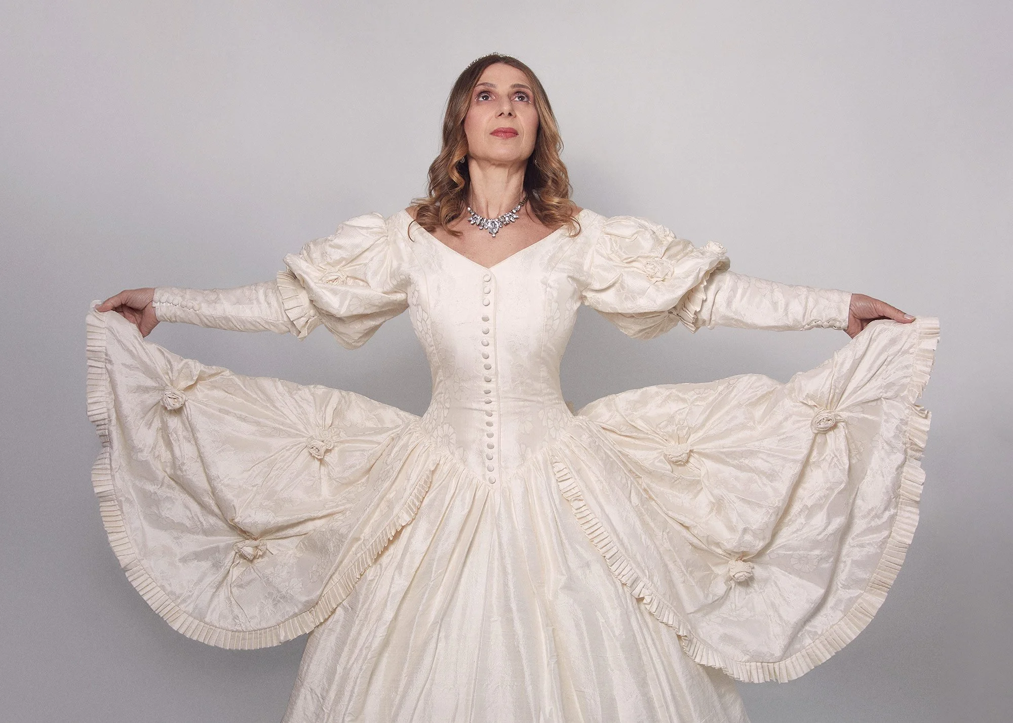 Portrait photograph of La Quinceañera with arms extended like wings in a symbolic gesture from the series Cuerpo Vestido, Alma Desnuda by Beatriz Perez.