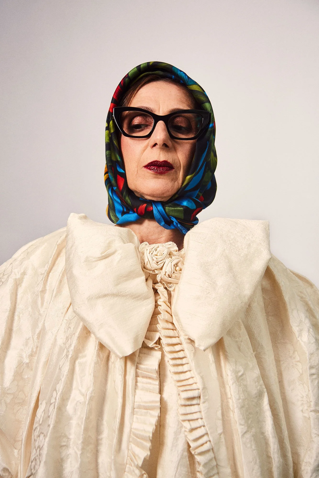 Portrait photograph of La Abuela wearing a tropical head scarf and glasses with eyes closed from the series Cuerpo Vestido, Alma Desnuda by Beatriz Perez.