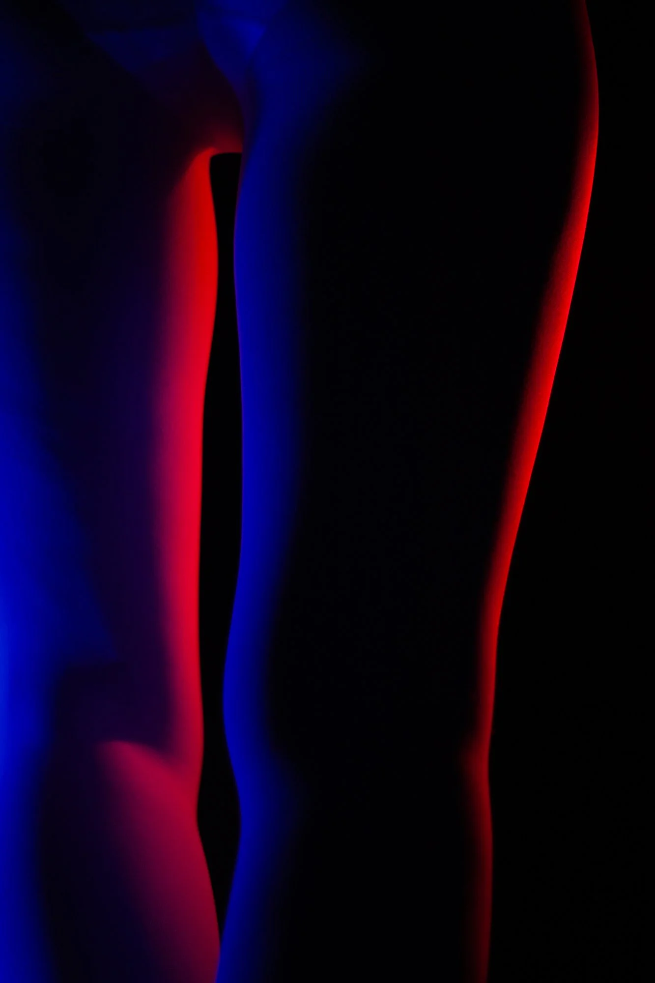 Abstract photograph of female legs illuminated in red and blue light from the conceptual photography series MISShapes by Beatriz Perez. 