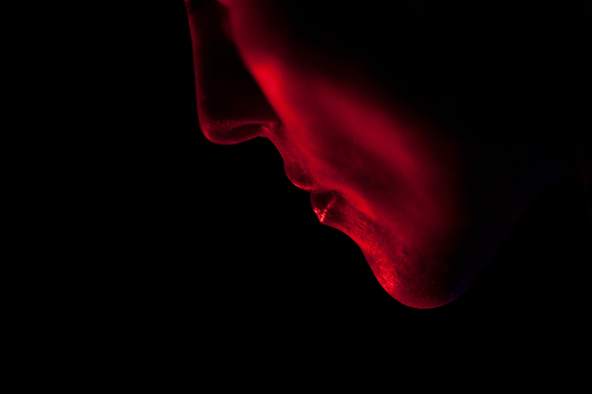 Side portrait photograph of a female face illuminated in red light from the conceptual photography series MISShapes by Beatriz Perez.