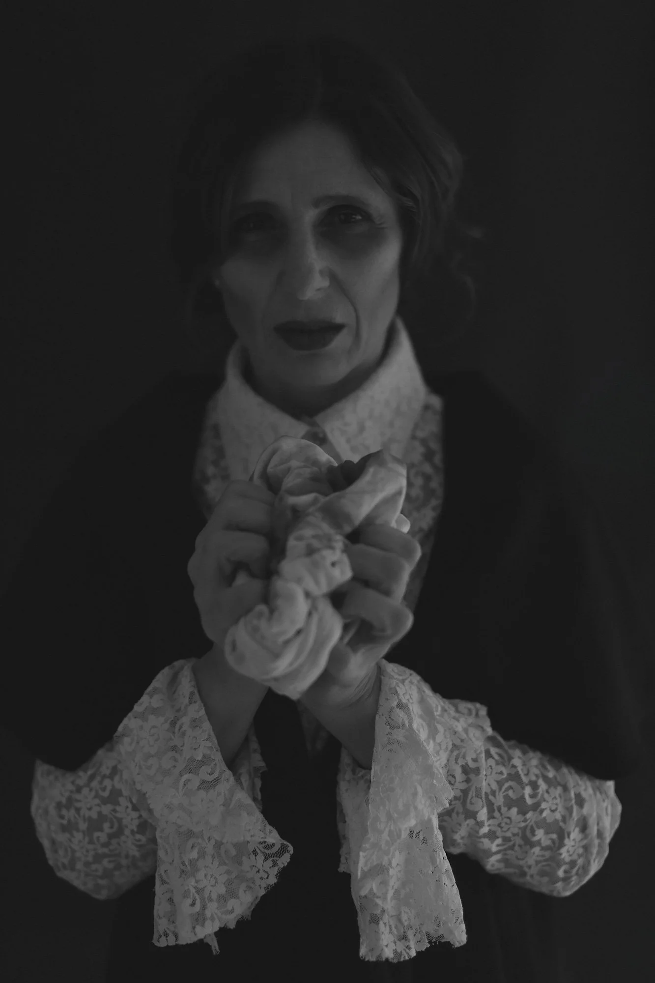 Woman holding a blood-stained white T-shirt close to her chest in a portrait from The Weeping Woman series by Beatriz Perez.