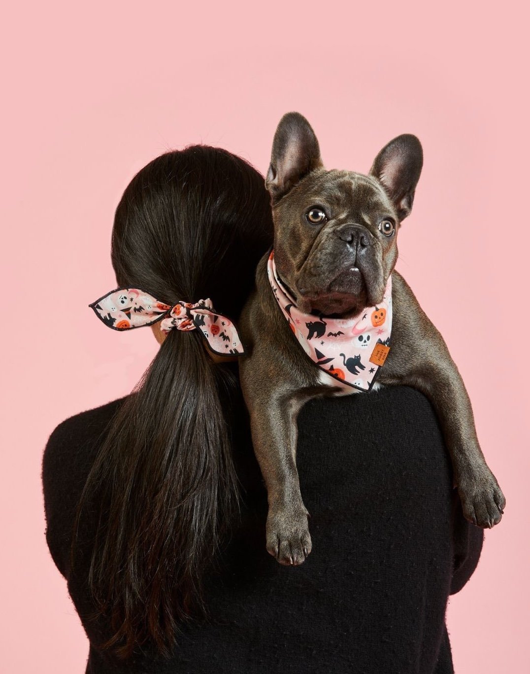woman holding a dog in a pink patterned halloween bandana