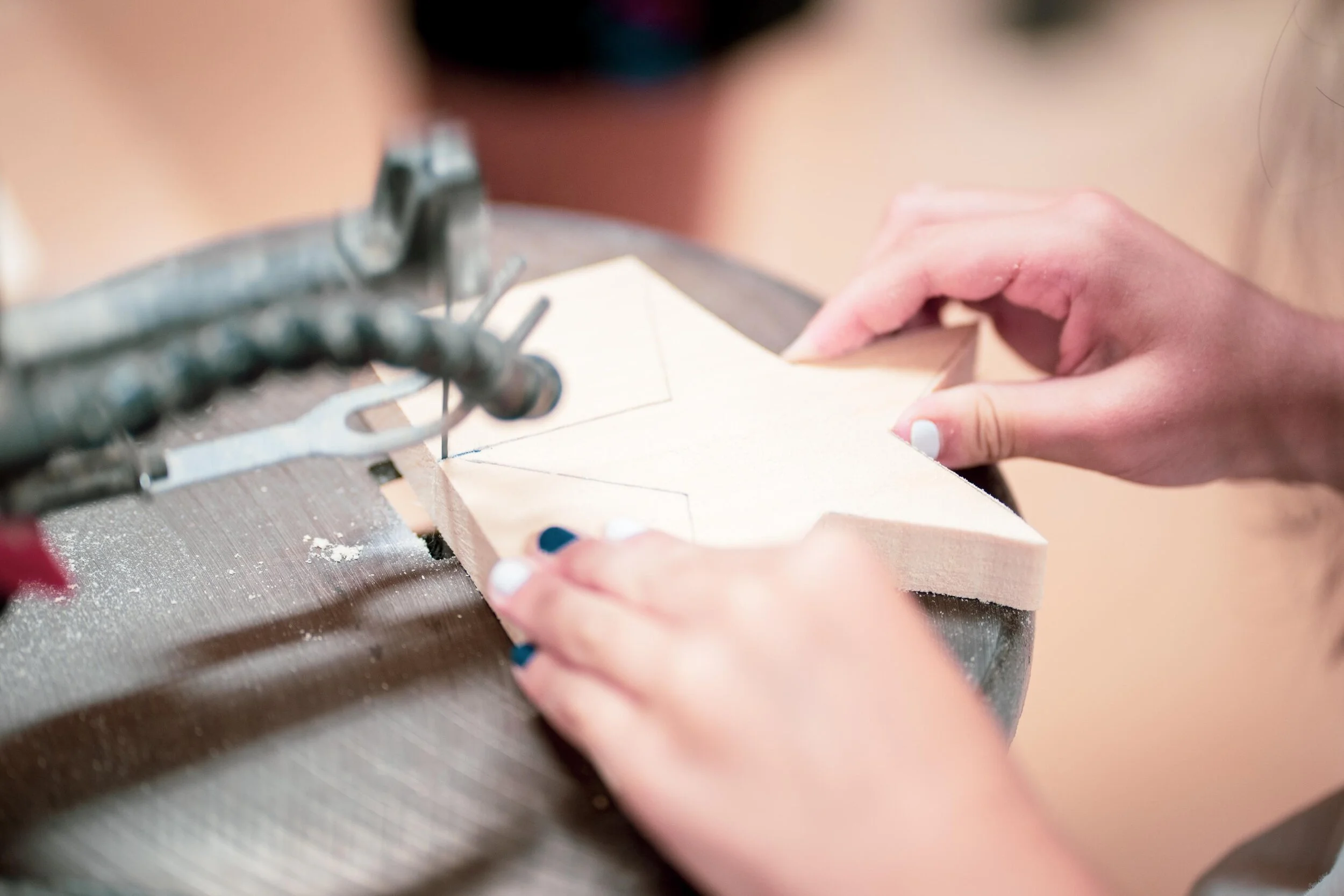 A person is cutting a piece of wood with a saw, shaping an outline on the wood.
