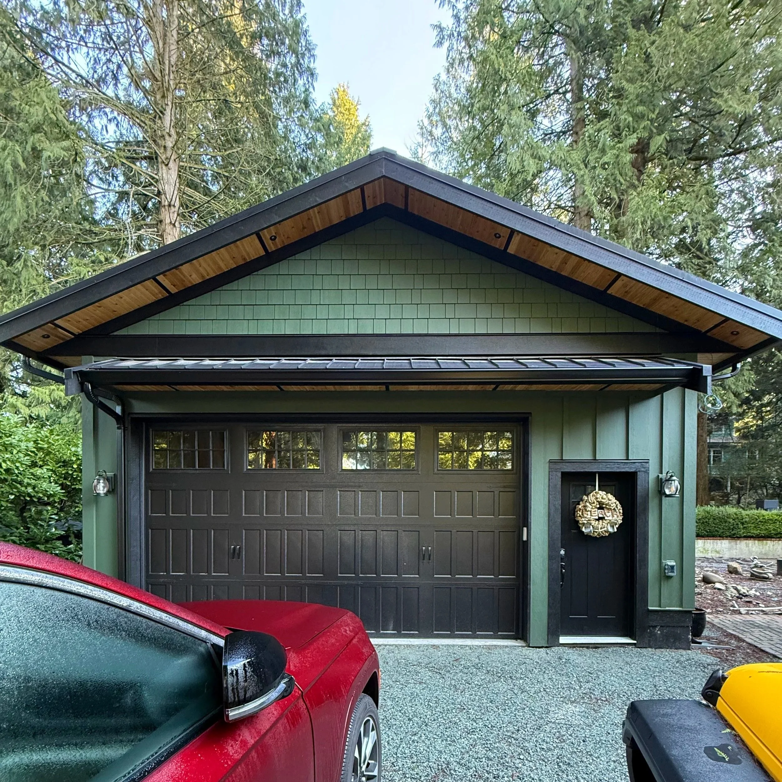 New-build garage with green board and batten, shingles, and cedar soffit. 