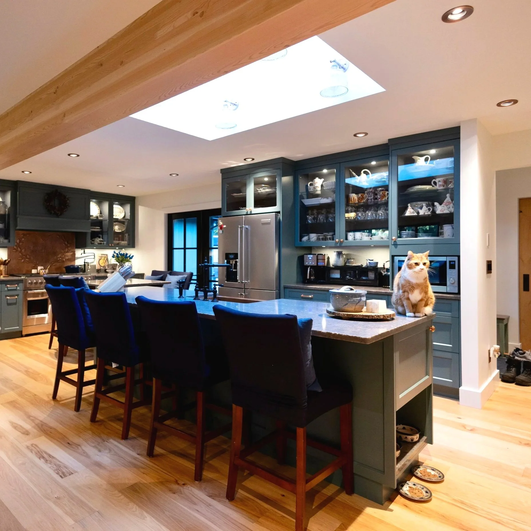 Bright, open kitchen with engineered oak hardwood floors, custom milwork, quartz countertops, a skylight, and an LVL beam. 