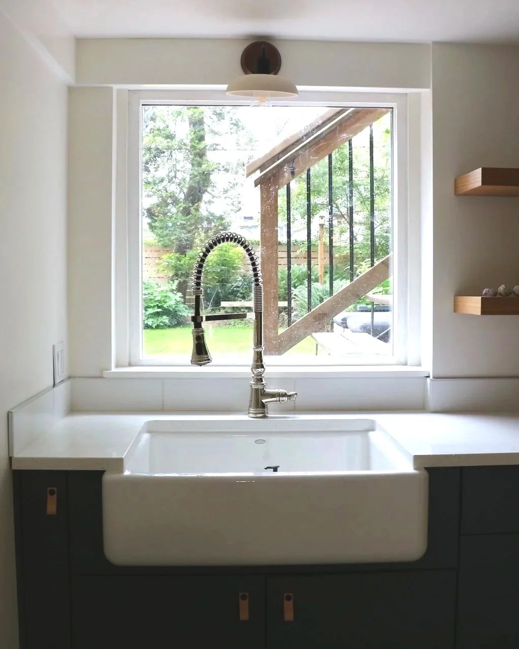 Farmhouse sink with a window overlooking a backyard with trees to bring in extra sunlight while creating a focal point.