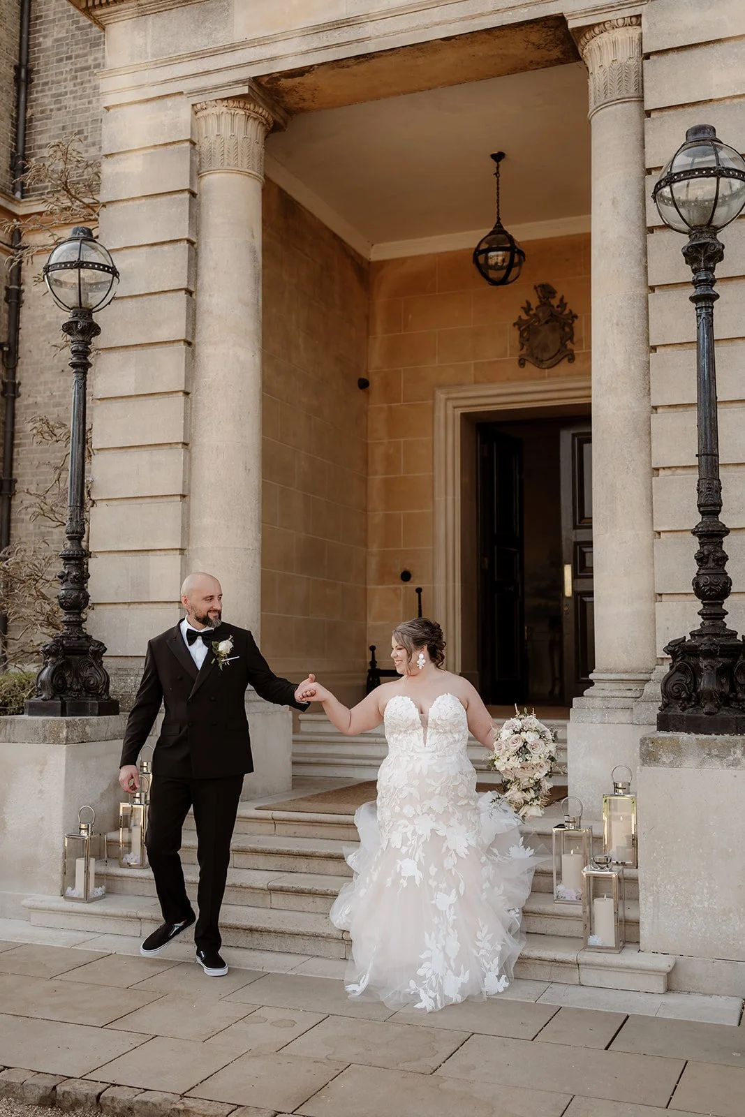 a bride and groom walk hand-in-hand down the steps at the doorway of Hedsor House wedding venue