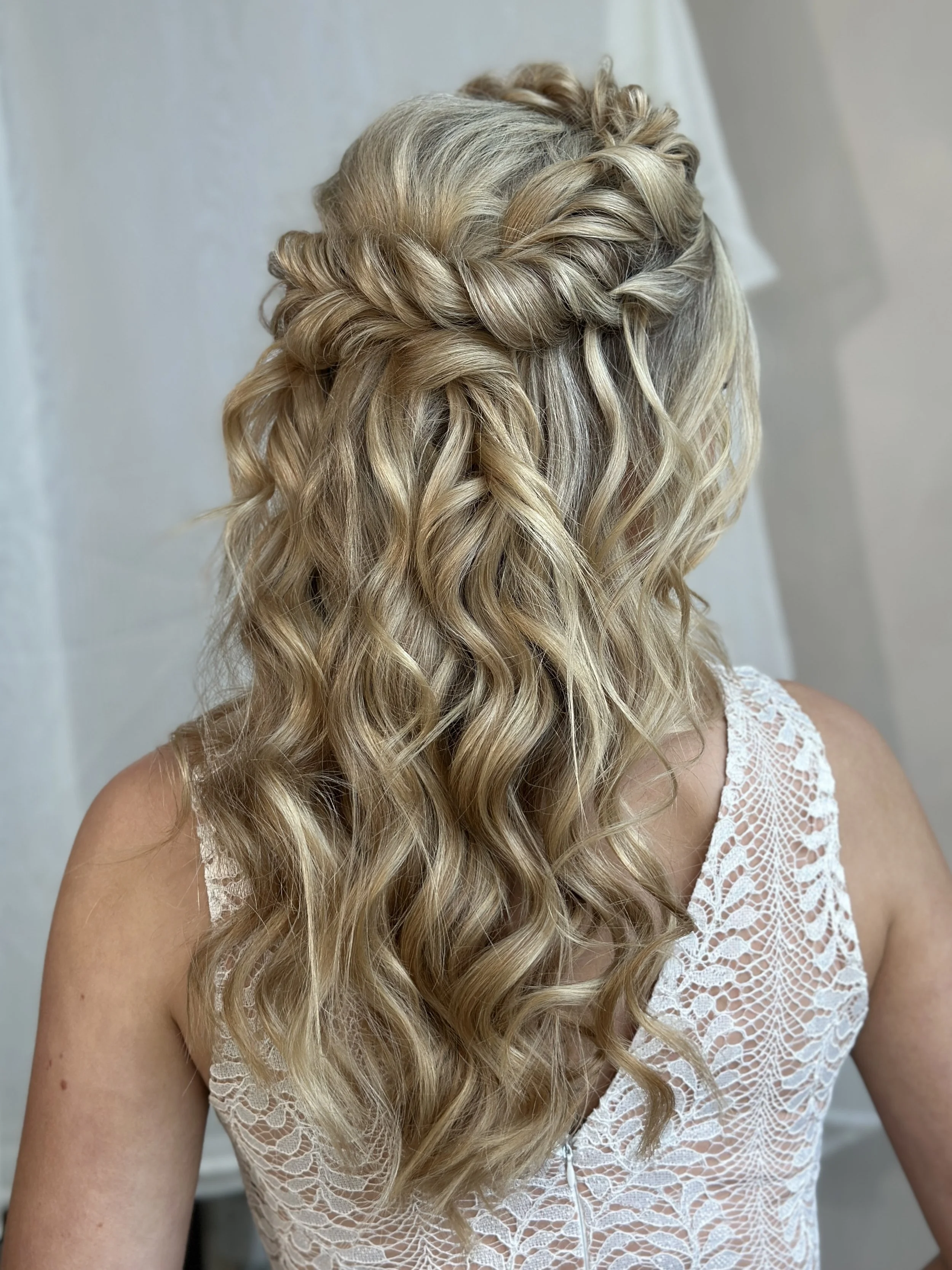 Back view of a boho hairstyle with soft waves and braided detail on blonde hair