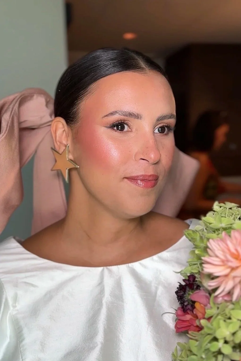 Image of a bride, with natural, glowy bridal makeup and an elegant undo, holding a colourful bouquet.