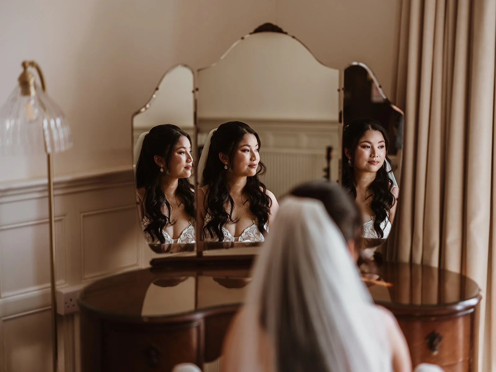 an image of a bride sitting infant of a mirror on a dressing table, with different views of her reflection